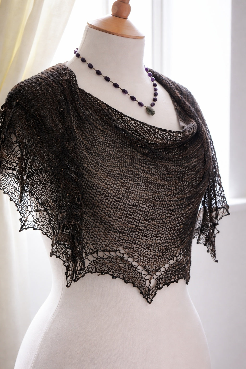 Black knitted shawl on a mannequin with a white background