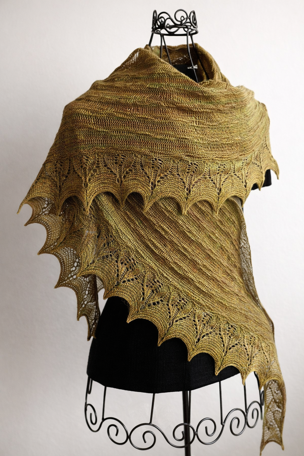 Knitted shawl with intricate pattern on a mannequin against a plain background